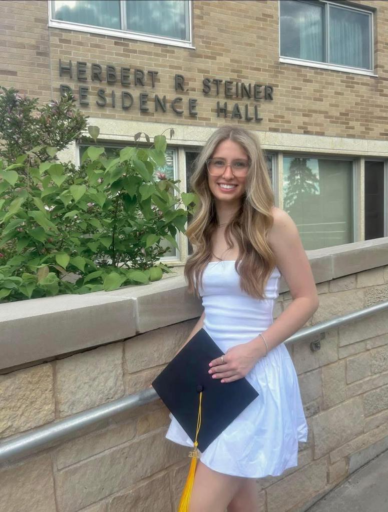 Photo of Eliotte Heinz in front of Herbert R. Steiner Residence Hall.